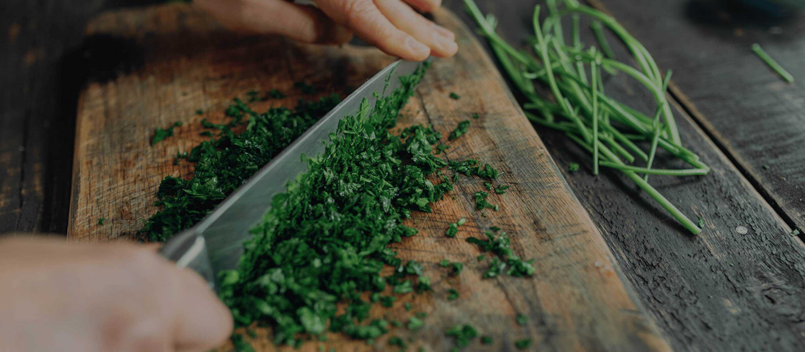 parsley being chopped on a wooden board