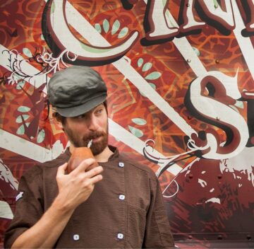 a man eating a donut in front of a truck.