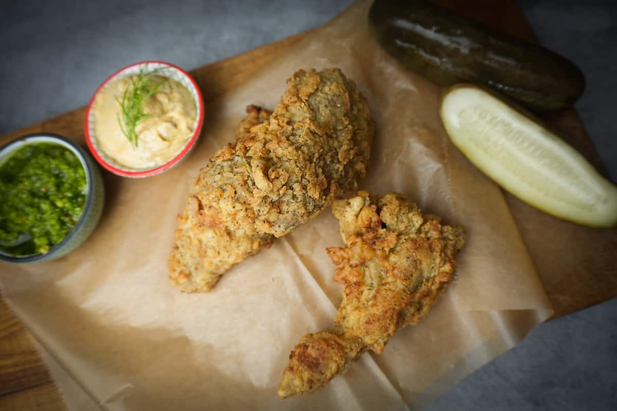 2 pieces of vegan Fried Chicken with dramatic lighting on craft paper.