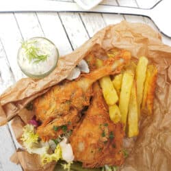 Vegan fried chicken and french fries in a brown paper bag.