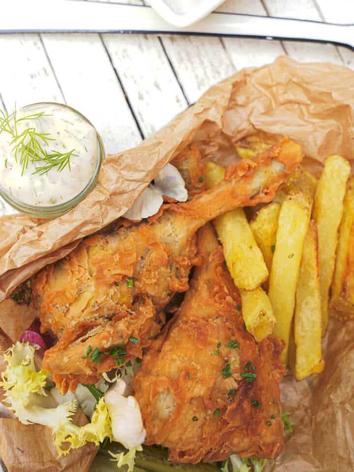 Vegan fried chicken and french fries in a brown paper bag.