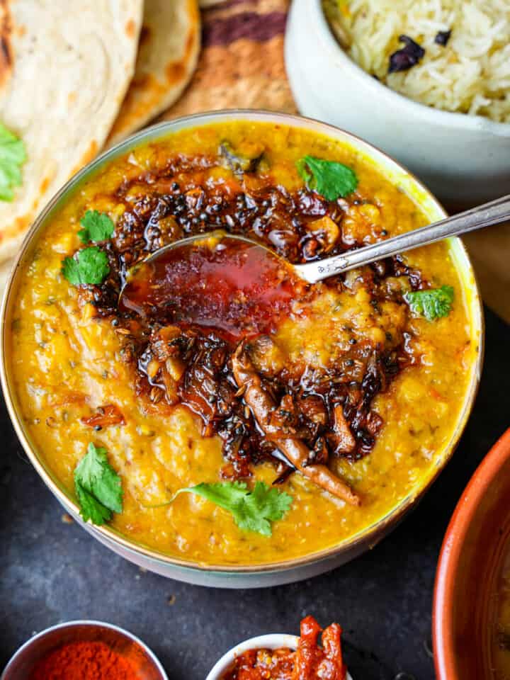 Arhar Dal with spoon. Roti, rice and condiments on the side.