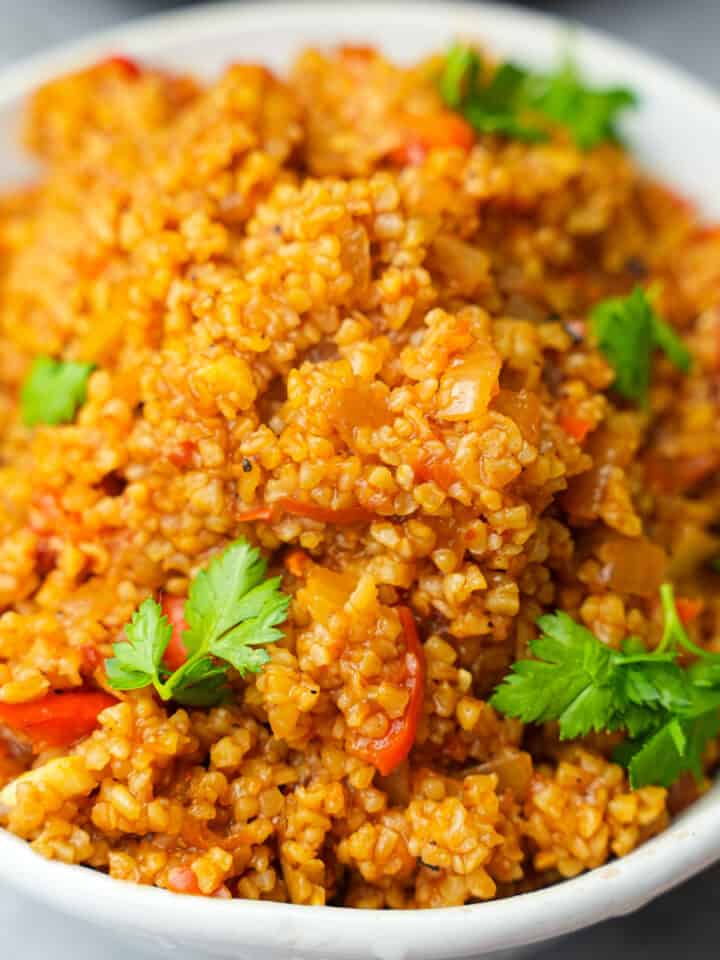 Bulgur Pilavi garnished with fresh parsley leaves in a white bowl.