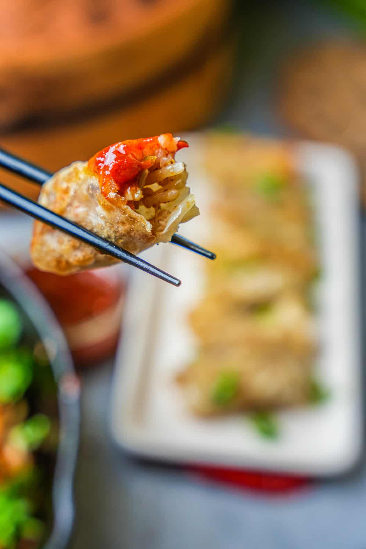 rice dumpling with chili sauce being eaten with chopsticks.