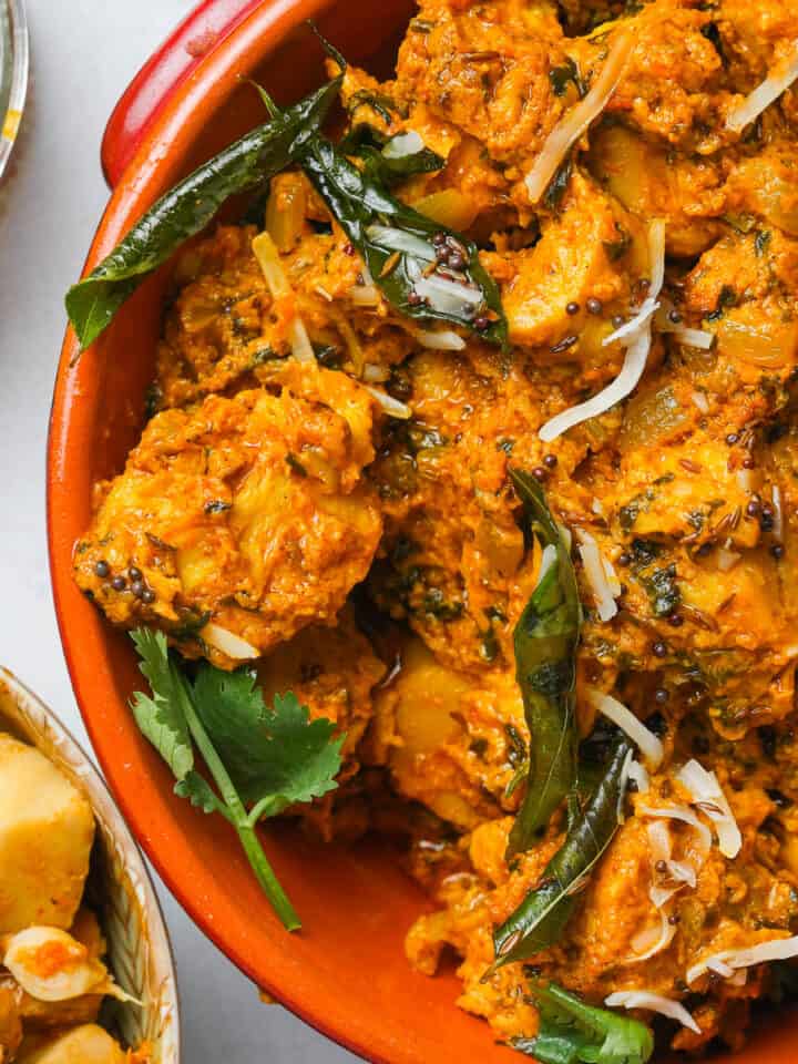 An orange bowl of soya chaap curry on a table.