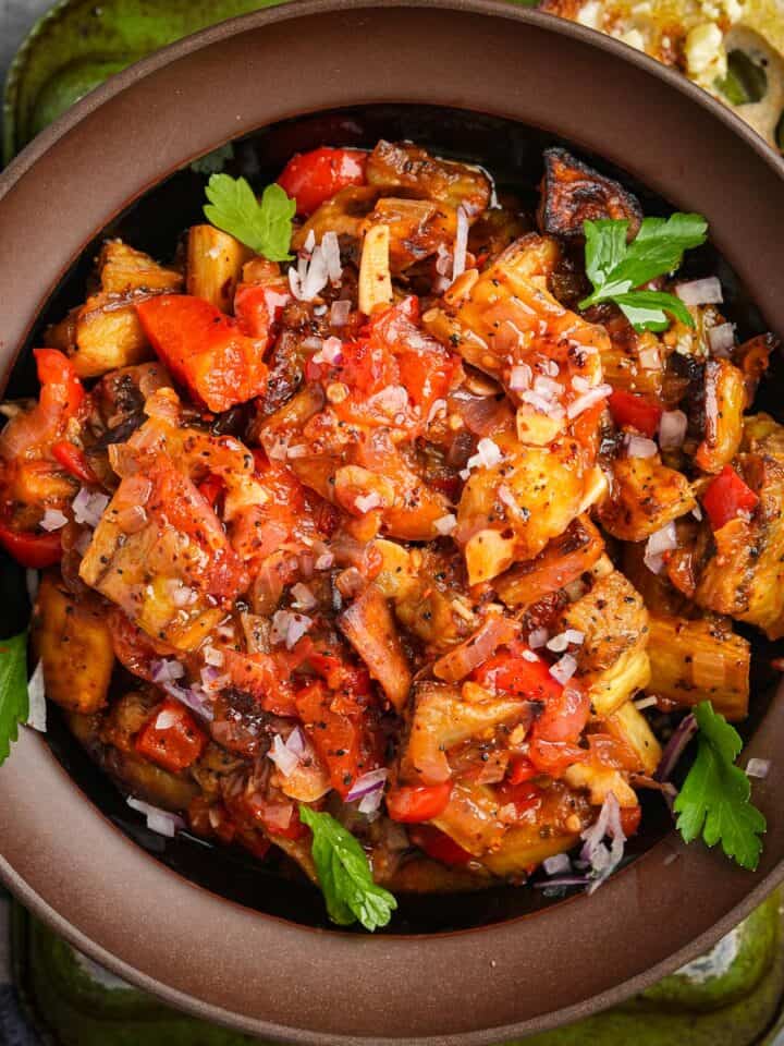 A bowl filled with Soslu Patlican and herbs.