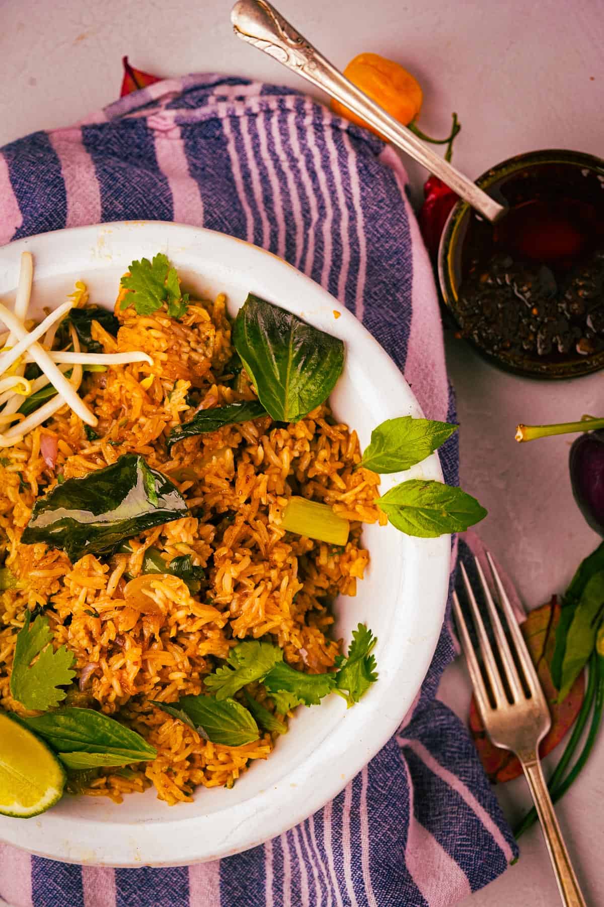 Khao pad fried rice on a plate with cucumbers and limes.