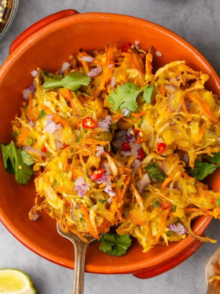A bowl filled with bakwan sayur garnished with chilies, minced shallots, and cilantro.