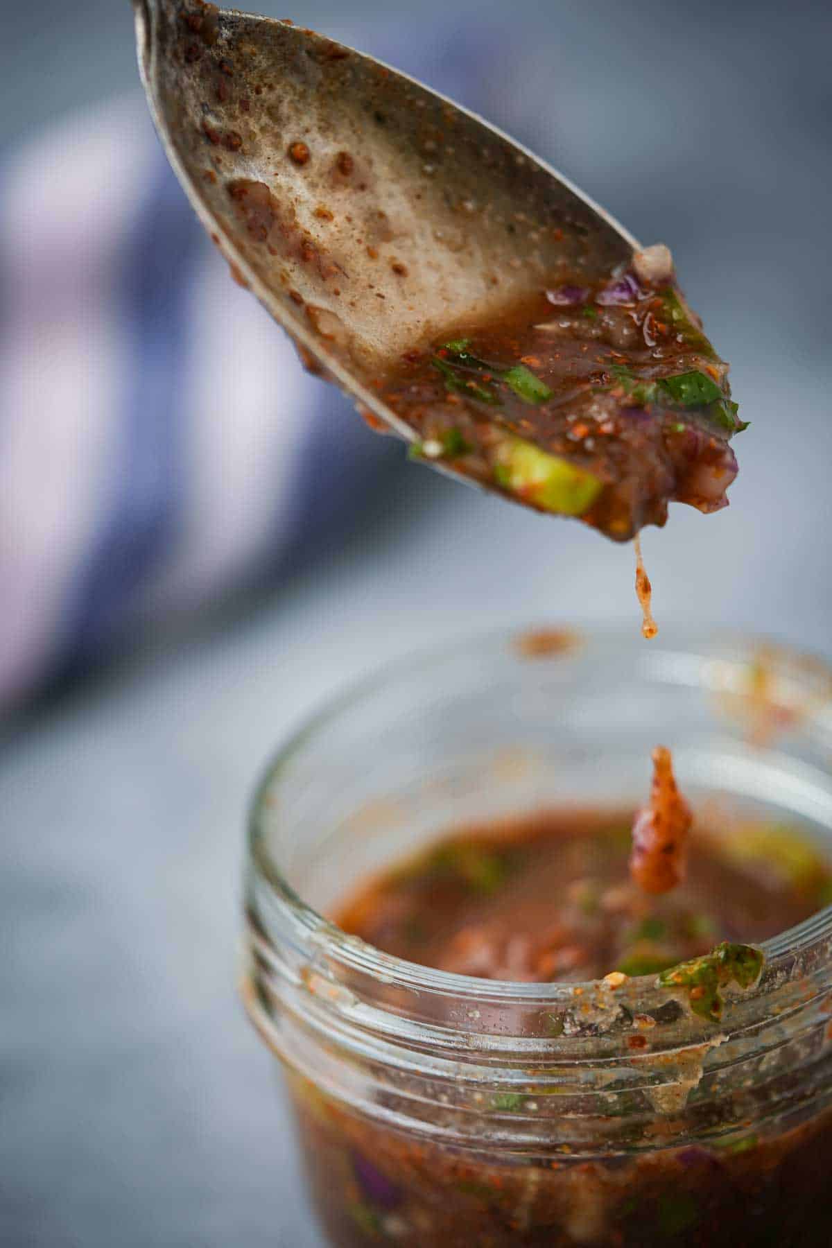 A spoon is being dipped into a jar of nam jim jeaw.