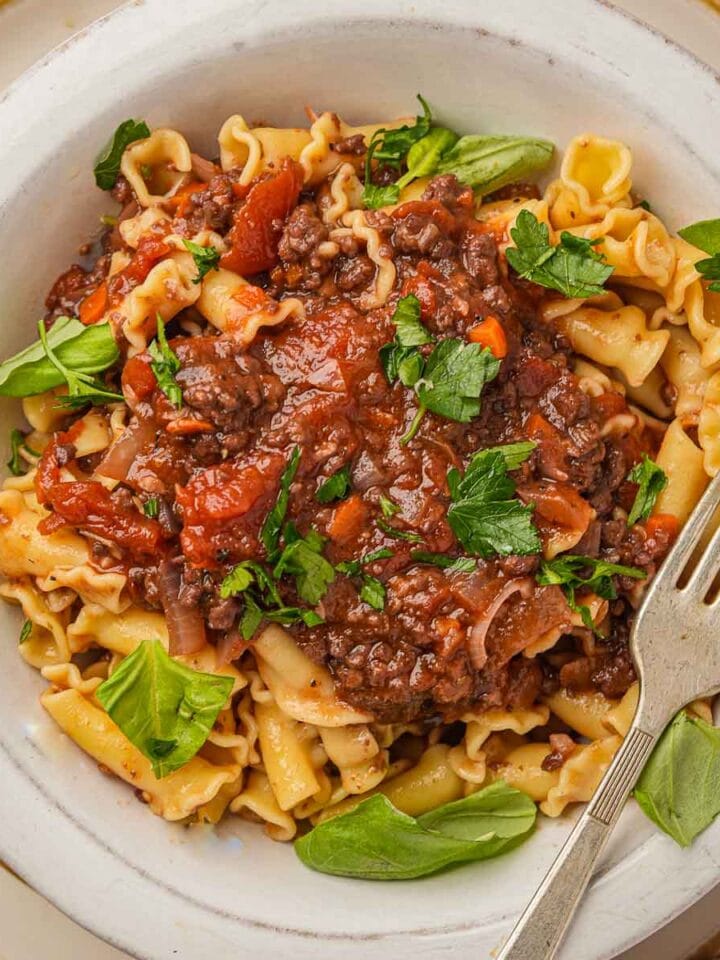 A bowl of pasta with Vegan Bolognese Sauce and basil.