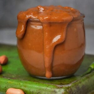 An overflowing jar of Vietnamese peanut sauce on a green tray.