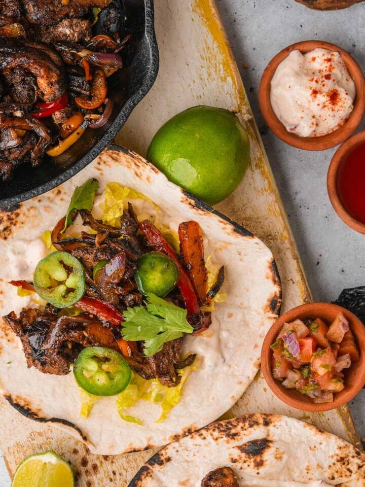 Vegan fajitas made with mushrooms on a wooden cutting board.