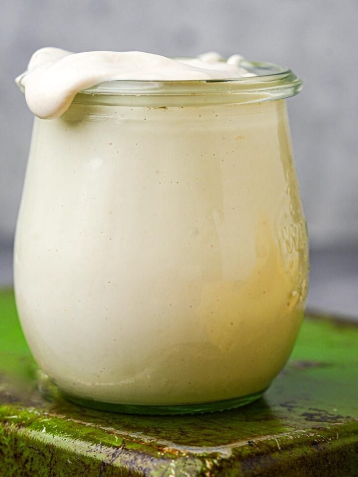 A jar of vegan mascarpone on a green tray.