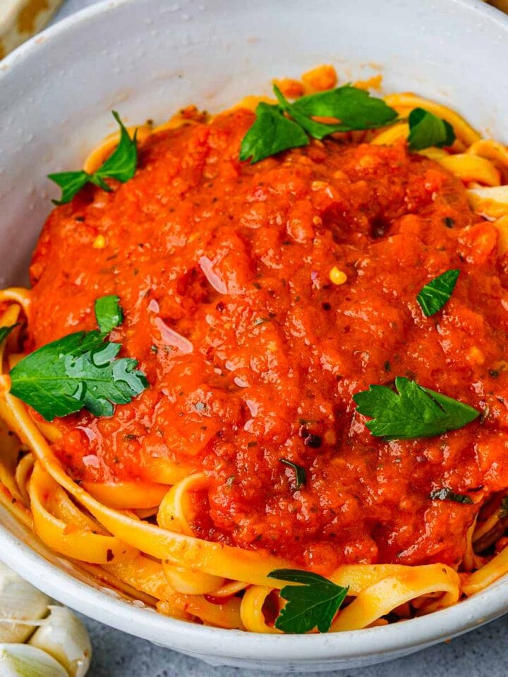 A bowl of fettuccine pasta topped with Vegan Marinara Sauce and fresh herbs.