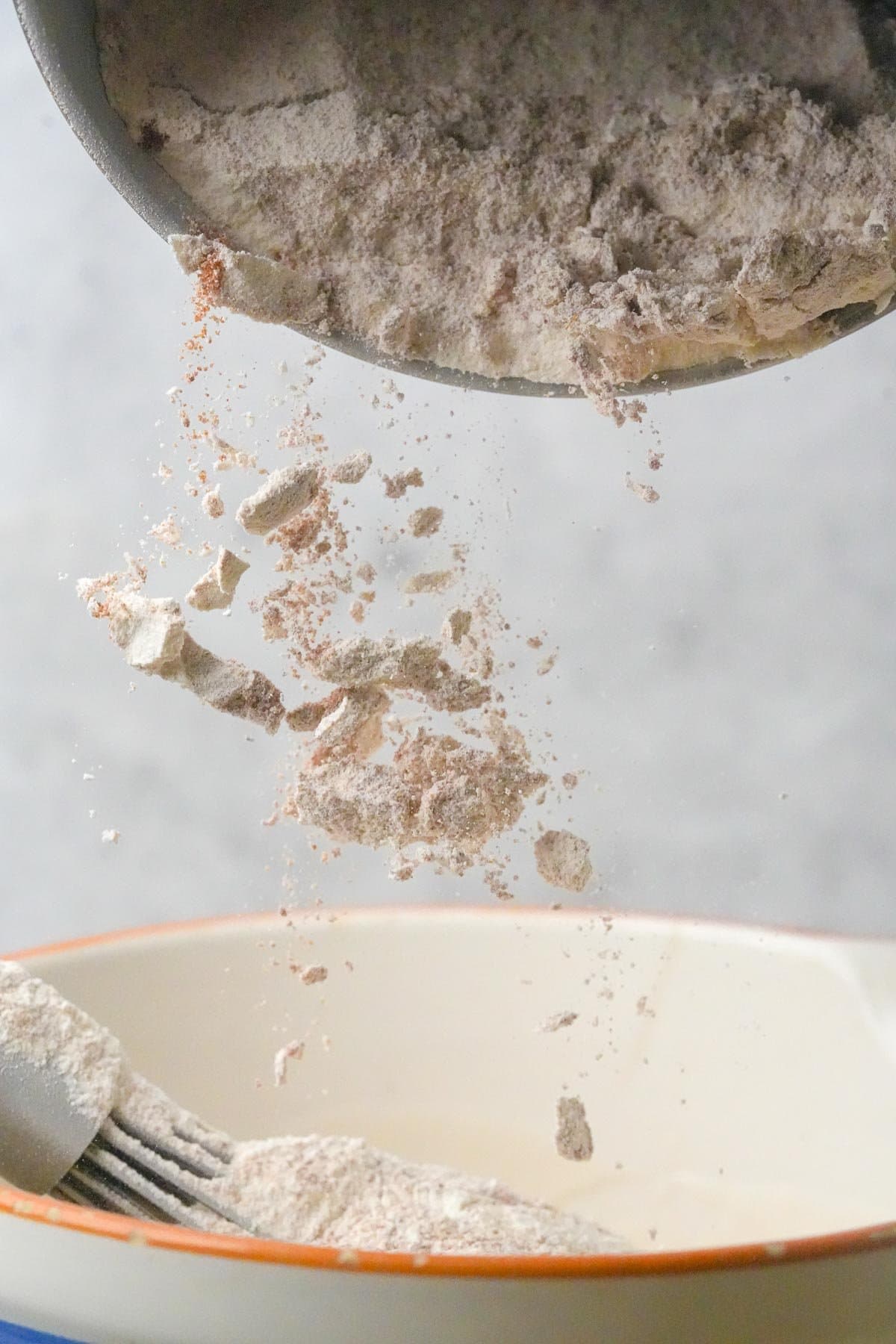 Flour being poured from one bowl into another, capturing particles mid-air.