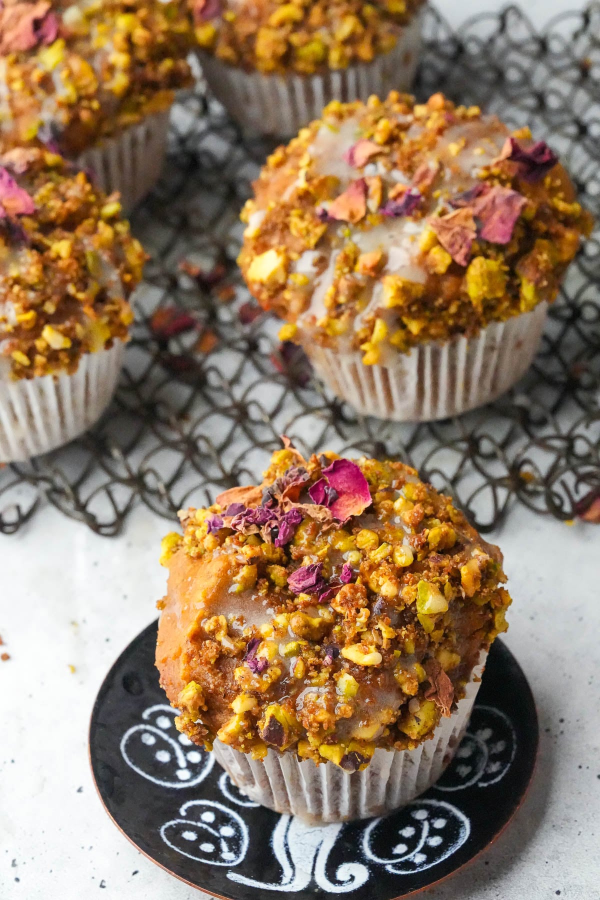 Vegan Pumpkin Muffins with a crumbly topping and decorative rose petals are cooling on a wire rack.