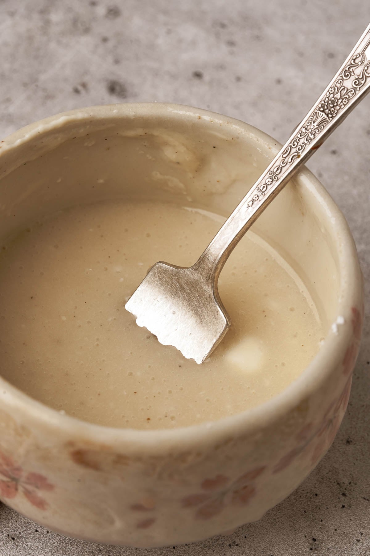 A small bowl filled with a freshly mixed cardamom glaze.