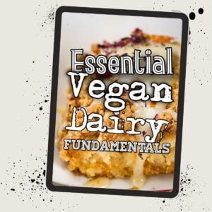 Image of a book cover titled "Essential Vegan Dairy Fundamentals" featuring a close-up of a dairy-free food item with a textured background.