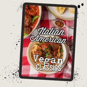 A cookbook cover titled "Italian American Vegan Classics" featuring plates of spaghetti with tomato sauce and meatballs, and a piece of bread on a red and white checkered tablecloth.