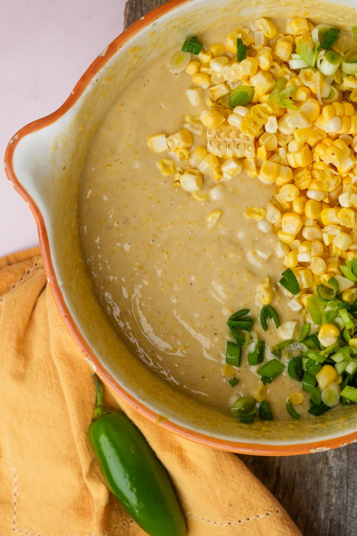 Vegan cornbread batter getting scallions and fresh corn mixed into it.