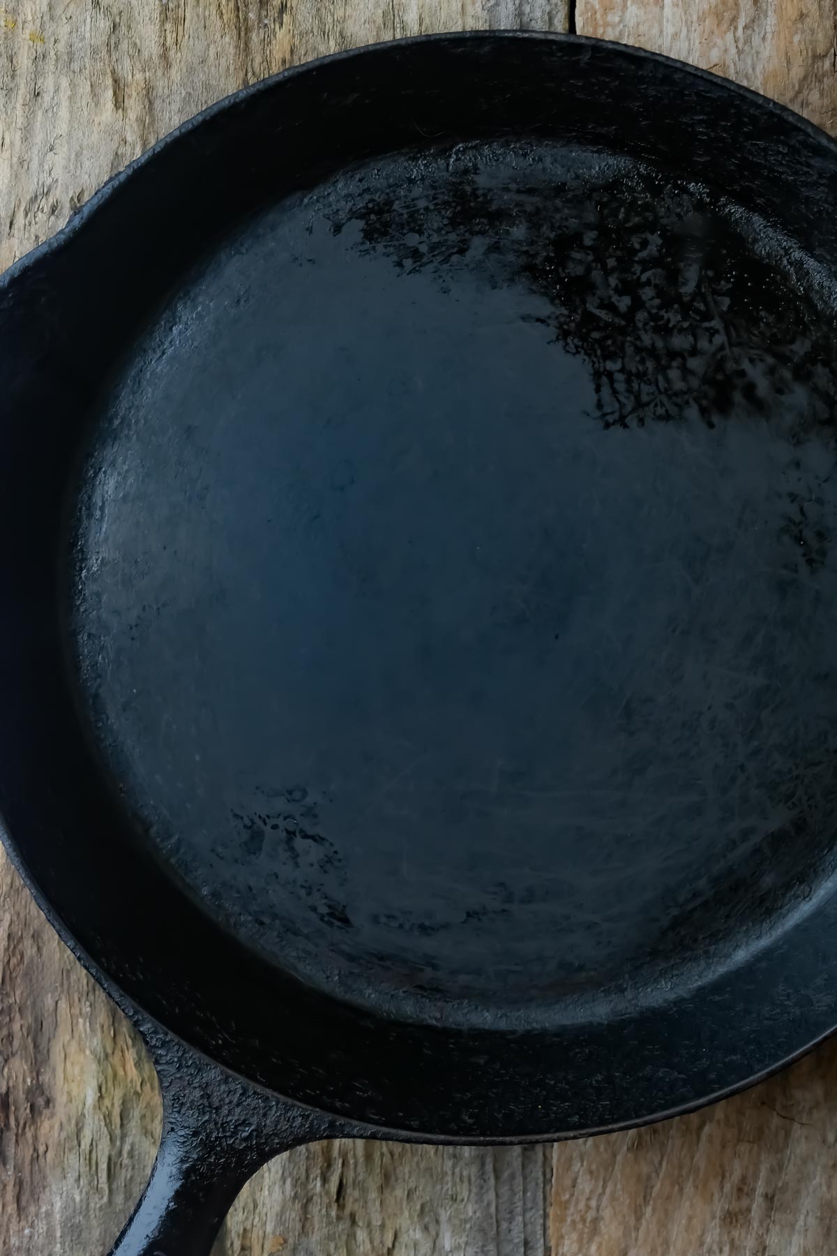 A well-seasoned black cast iron skillet placed on a wooden surface.
