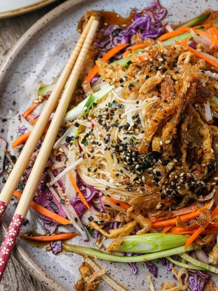A plate of somen salad with shredded vegetables, sesame seeds, and chopsticks on the side.