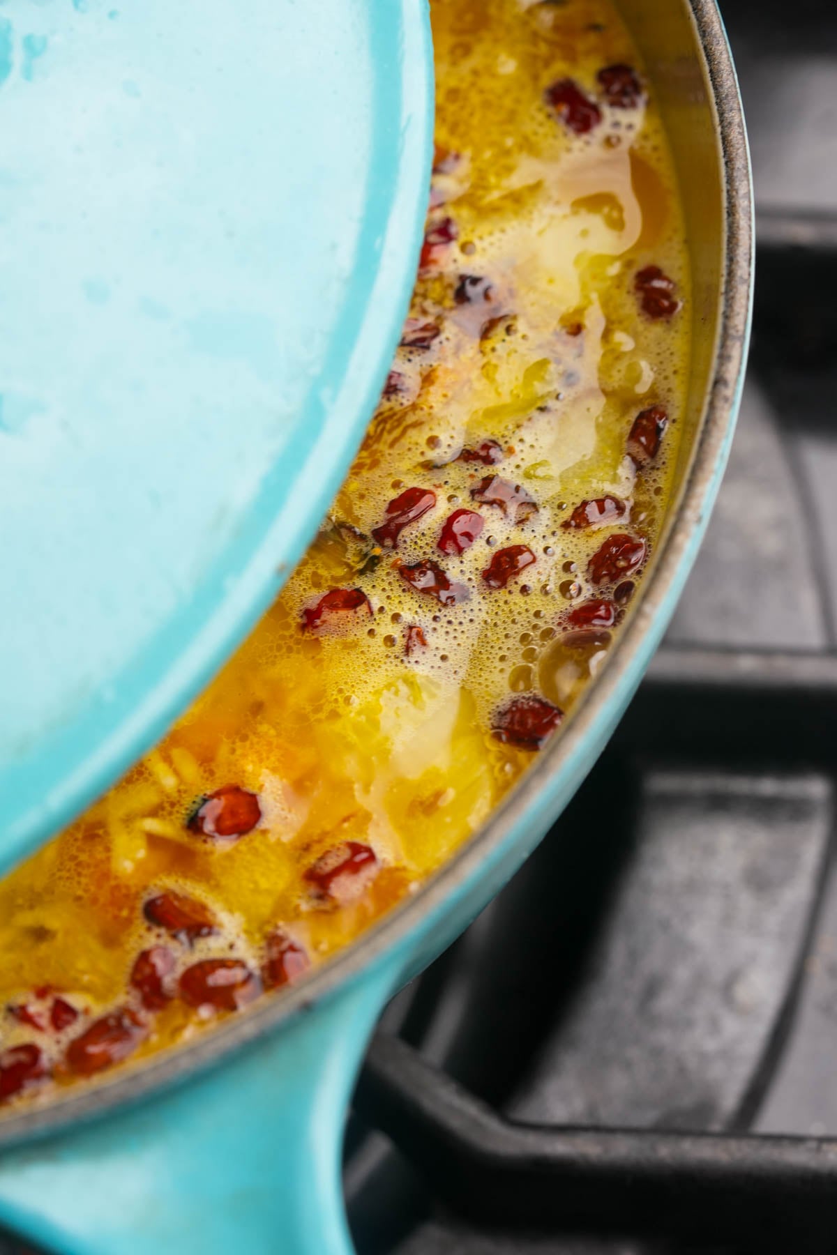 A blue pot partially covered with a lid sits on a stove, containing simmering Moroccan rice.